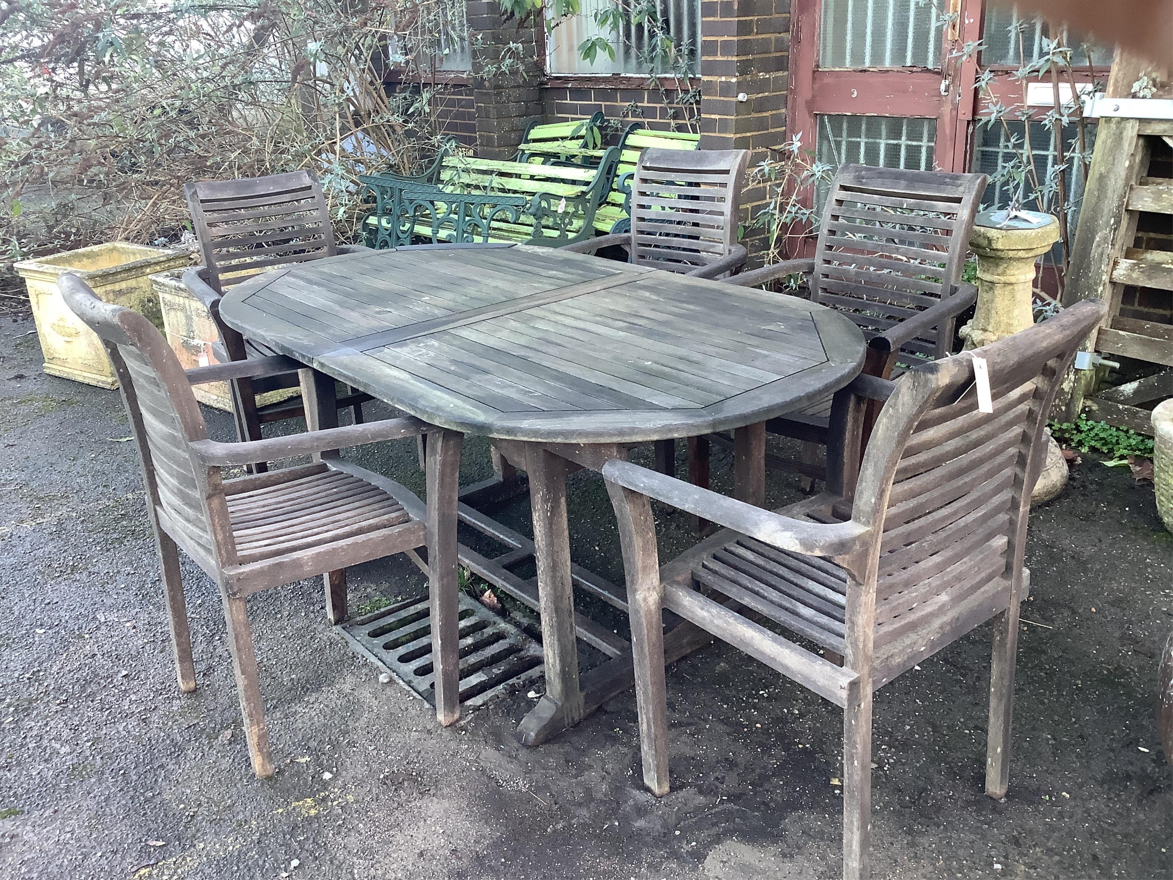 A teak extending garden table, width 180cm, depth 100cm, height 75cm, and five elbow chairs. Condition - fair